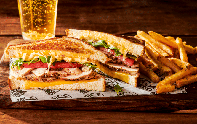 two halves of a chicken sandwich with fries and a beer